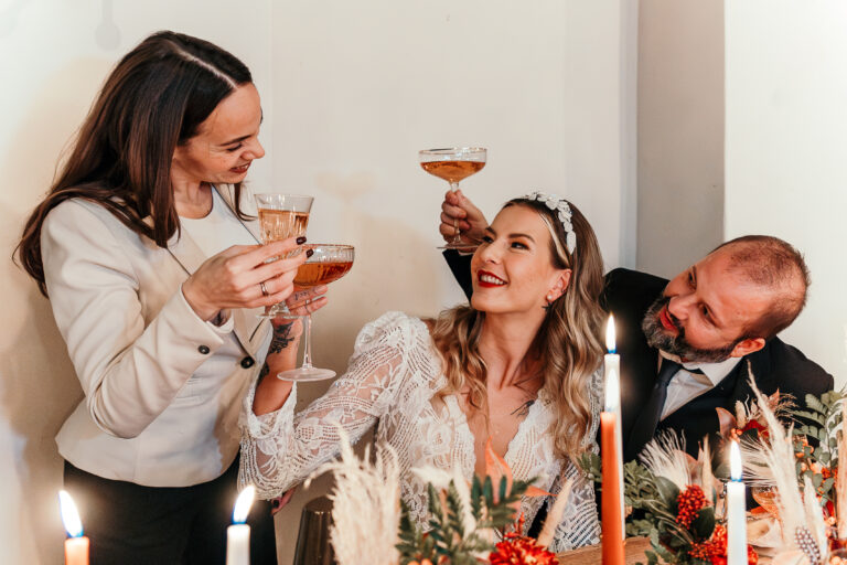 Hochzeitsplanerin stößt mit Brautpaar an.