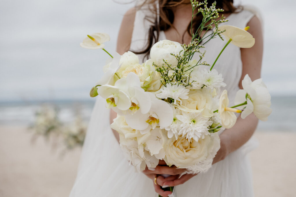 Hochzeit am Strand Norddeutschland.Braut hält Strauß mit weißen Blumen.
